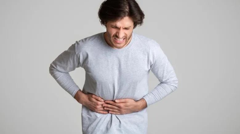 Muž drží břicho v bolesti při zánětu střev