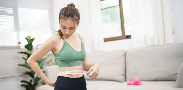 Žena měří pas v domácím prostředí při sledování metabolizmu.