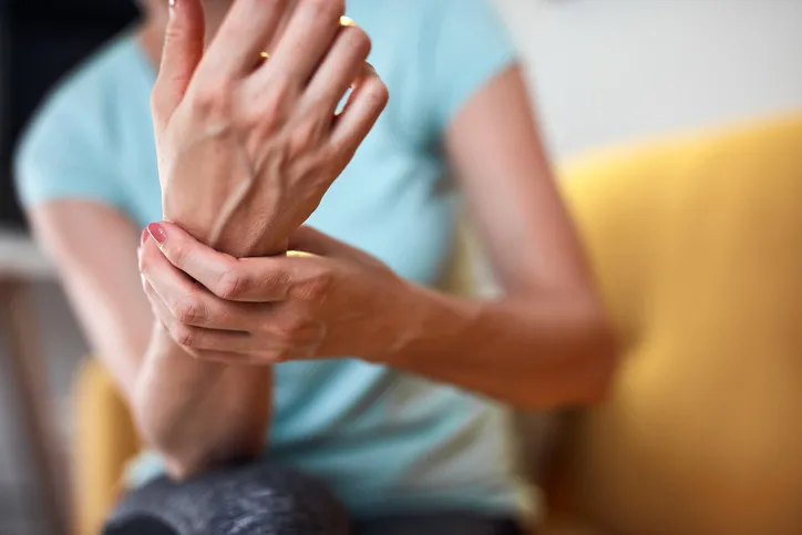 Žena drží ruku v bolesti kvůli příznakům periferní neuropatie.