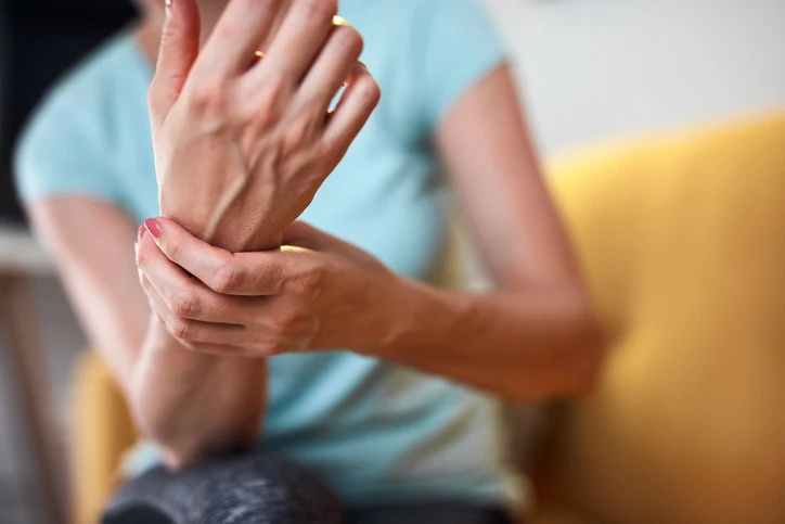 Žena drží ruku v bolesti kvůli neuropatii ruky.