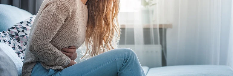 Žena drží břicho v bolesti - příznak endometriózy.