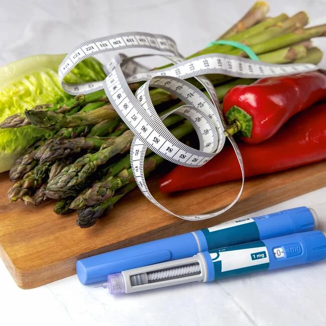 Zelenina s měřicí páskou a injekční tužkami na diabetiky.