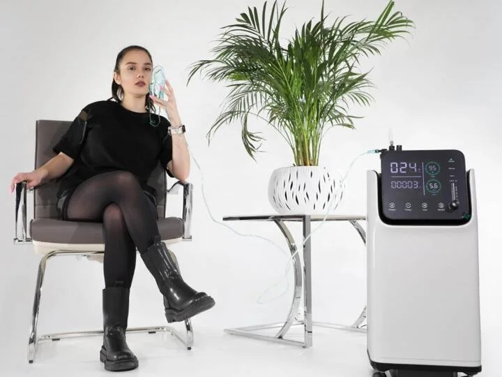 Žena používá přenosný kyslíkový koncentrátor s maskou pro terapii.