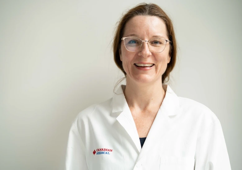 Žena v bílém plášti s logem Canadian Medical na světlém pozadí.