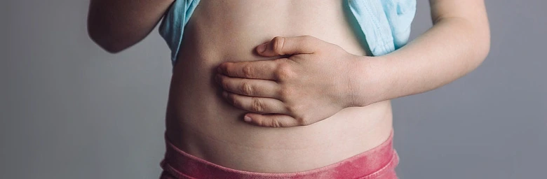 Dítě drží břicho v bolesti - příznak zánětu slepého střeva.