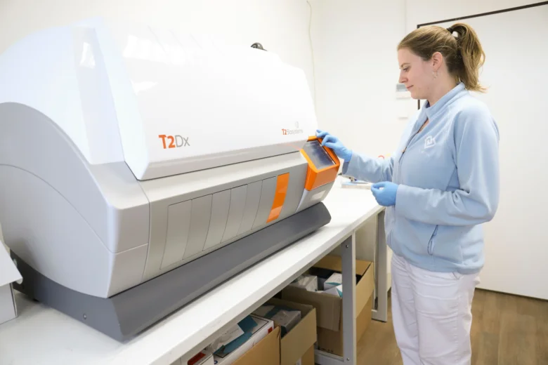 Žena v modrém oblečení ovládá lékařské diagnostické zařízení.