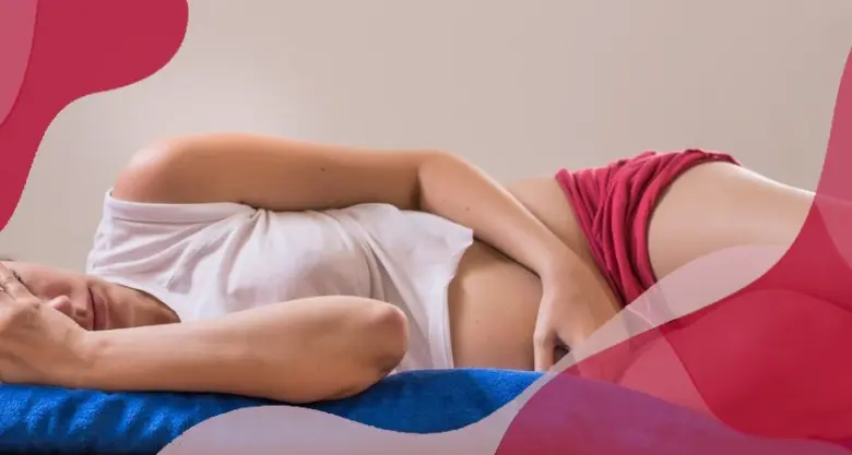 Těhotná žena leží na boku a drží si bolavé podbřišek.