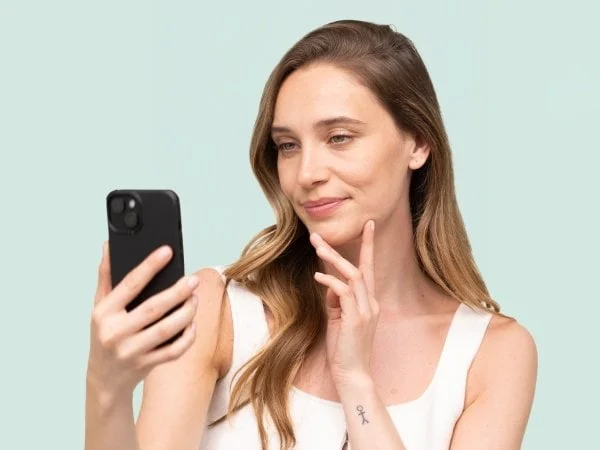 Žena se dívá na telefon s výrazem úvahy.