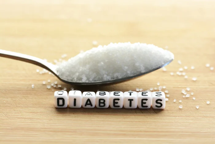Lžíce s cukrem vedle písmen tvořících slovo diabetes.