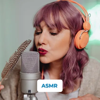 Žena s náušnicemi drží peří u mikrofonu pro ASMR nahrávání.