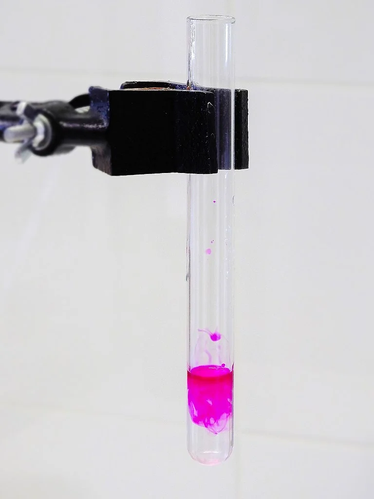 Testovací zkumavka s růžovým roztokem ukazující vysokou hodnotu pH.