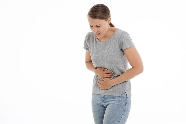 Žena drží břicho v bolesti při zánětu ledvin