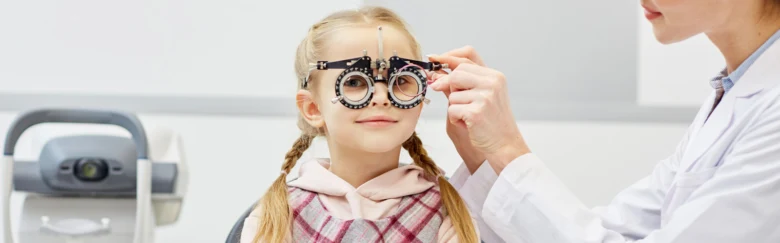 Dívka v pokoji s očima zkouší brýle na astigmatismus.