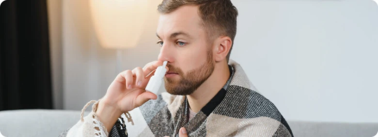 Muž používá nosní sprej pro léčbu zánětu nosohltanu.