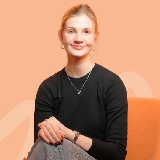 Žena sedící na pohovce s úsměvem.