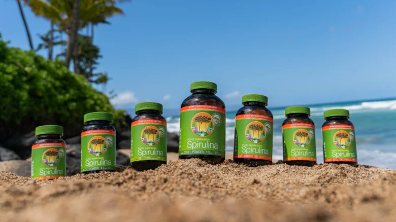Fialové lahve s spirulinou na pláži u moře.