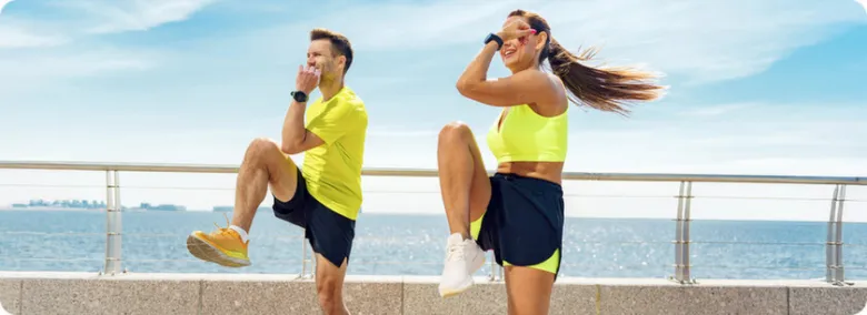 Muž a žena cvičí venku u moře v sportovním oblečení.