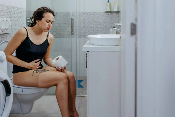 Žena sedí na záchod s příznaky průjmu.