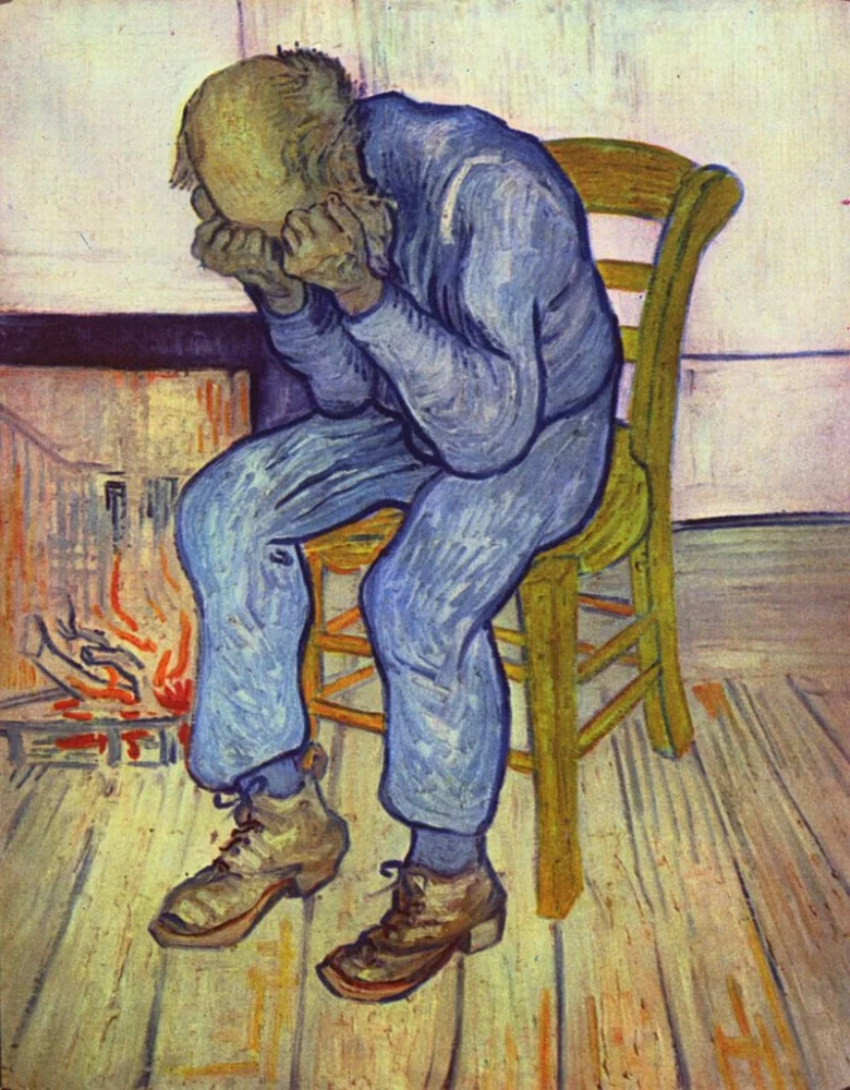 Muž sedící v křesle s hlavou skloněnou před krbem.