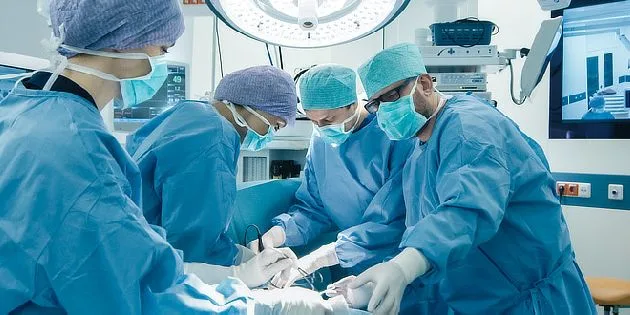 Tým chirurgů provádí operaci na pacientovi v nemocničním sále.