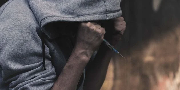 Person with syringe and hoodie