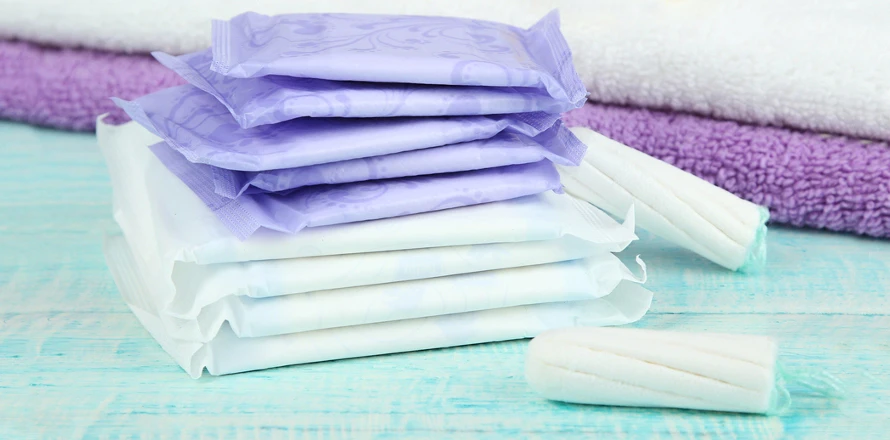 Sada menstruačních vložek, tampónů a ručníků na modrém povrchu.