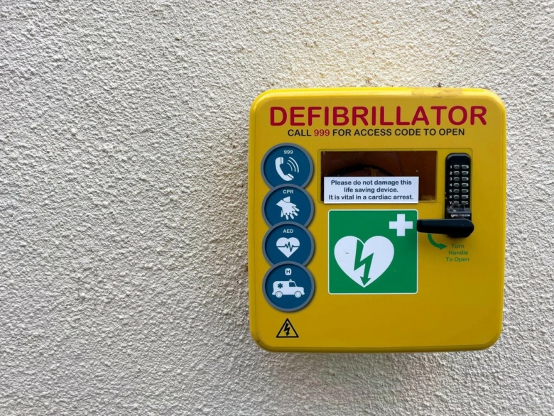 Žlutý defibrlátor na zdi pro resuscitaci při zásahu elektrickým proudem.