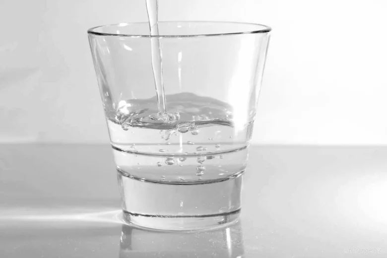 Voda se nalévá do sklenice na stůl.