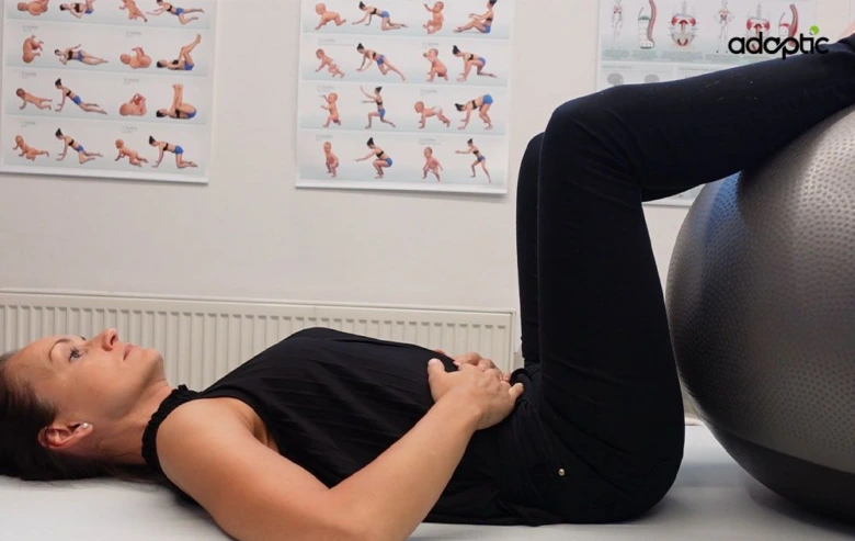Žena leží na zádech s nohama na fitbalu při cvičení pro bolesti zad.