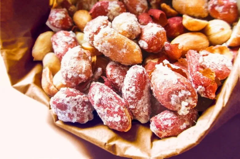 Opravené arašídy s cukrem v hnědém papírovém pytlíku.
