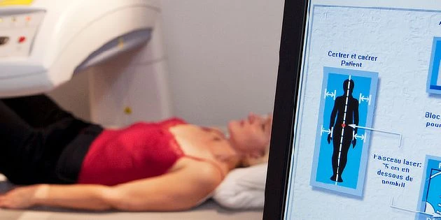 Žena leží v CT přístroji s informacemi o polohování těla.
