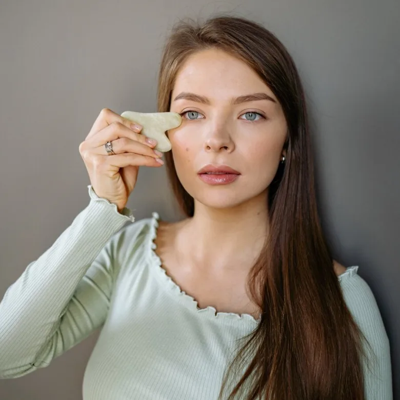 Žena používá kameň pro masáže obličeje na tvář.
