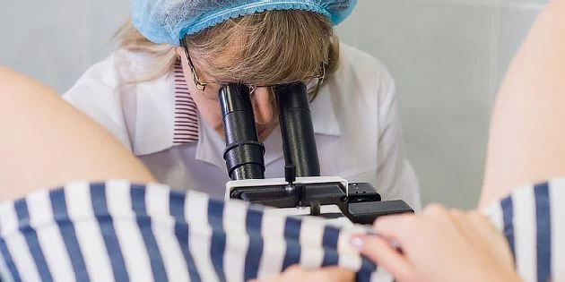 Gynekoložka zkoumá děložní čípek pomocí kolposkopu.