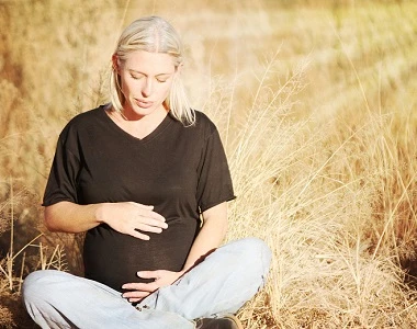 Pregnant woman sitting in field