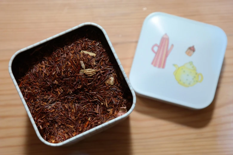 Suchá rostlinná surovina Rooibos čaj v plechové krabičce.