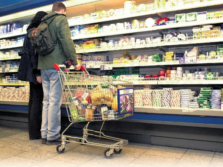 Dva lidé nakupují v supermarketu u chladničky.