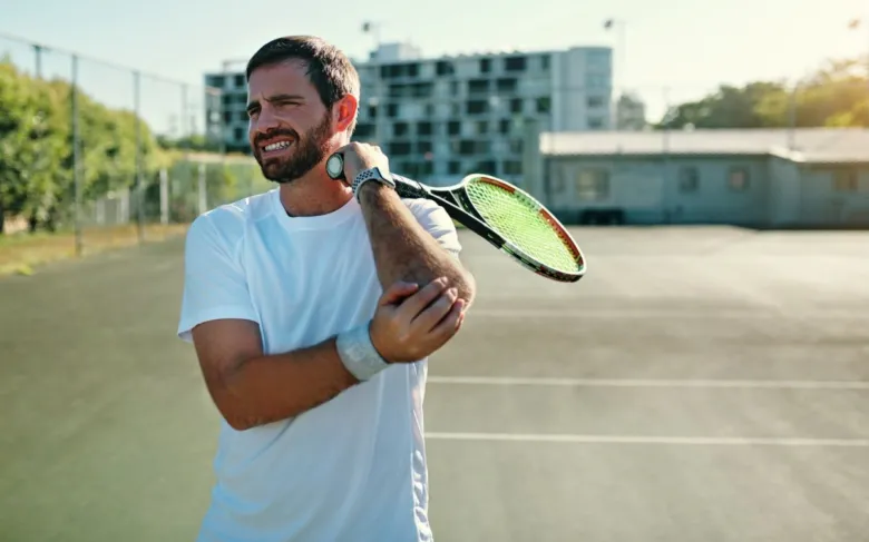 Man with tennis elbow pain holding racket