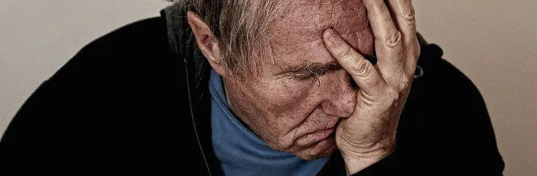Muž s rukou na čele vyjadřující deprese a duševní utrpení.