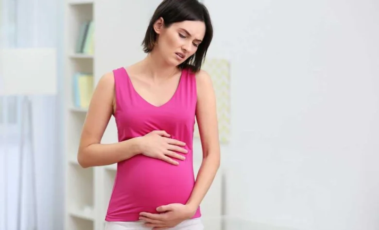 Těhotná žena drží břicho s možným bolestí vaječníku.