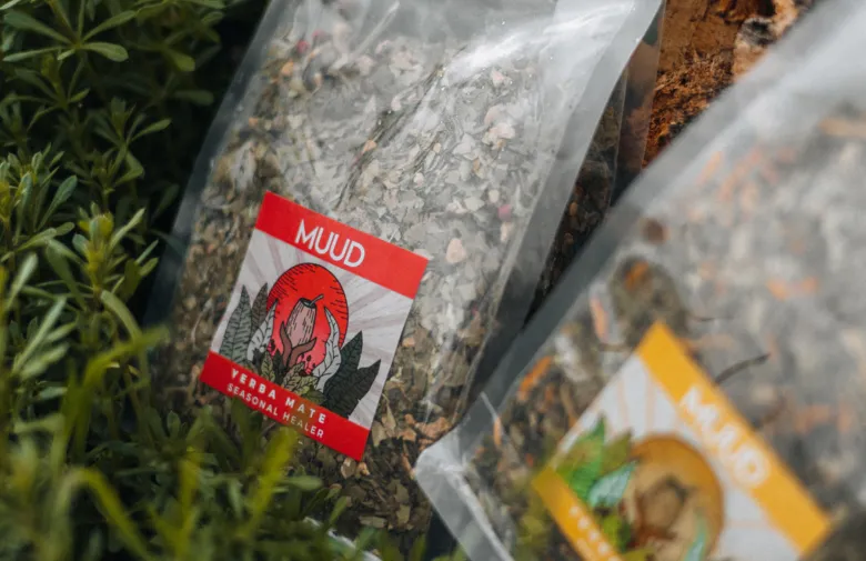 Dvě sáčky yerbamate čaje značky Muud mezi zelenou vegetací.