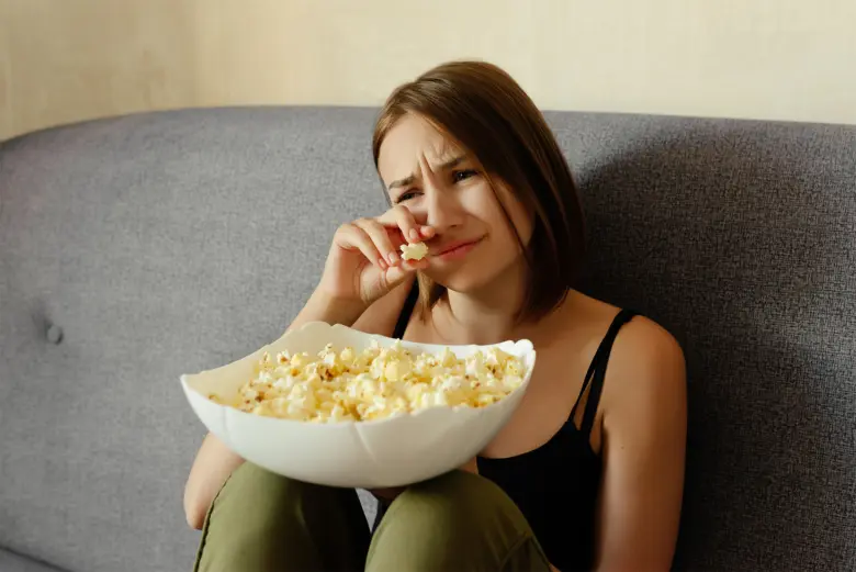 Žena sedí na gauči s mýdlem v ruce a vypadá nešťastně.