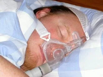Muž spí s přístrojem na léčbu spánkové apnoe.