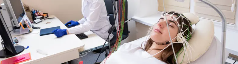 Žena leží na lůžku s elektroencefalografem pro vyšetření mozku.