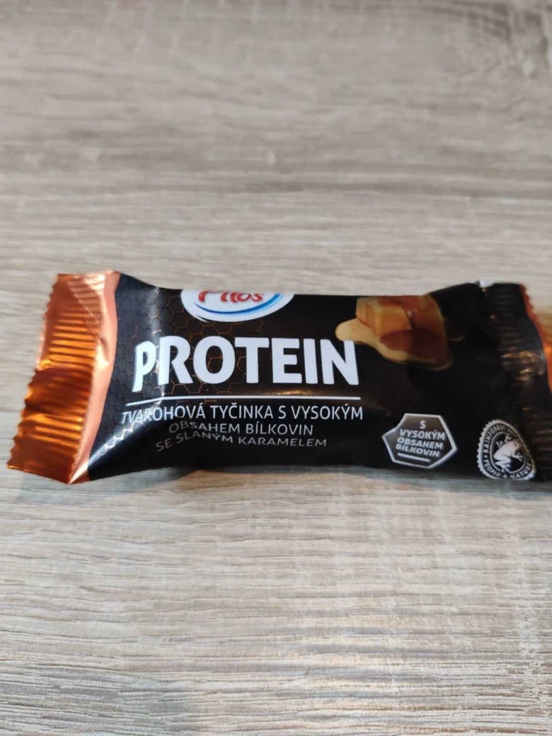 Proteinová tyčinka s karamelovým náplní na dřevěném povrchu.