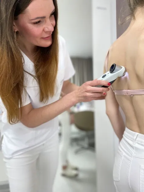 Dermatolog zkoumá znaménka na zádech pacienta pomocí digitálního přístroje.