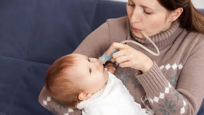 Žena používá elektrickou odsávačku hlenů na dítě.
