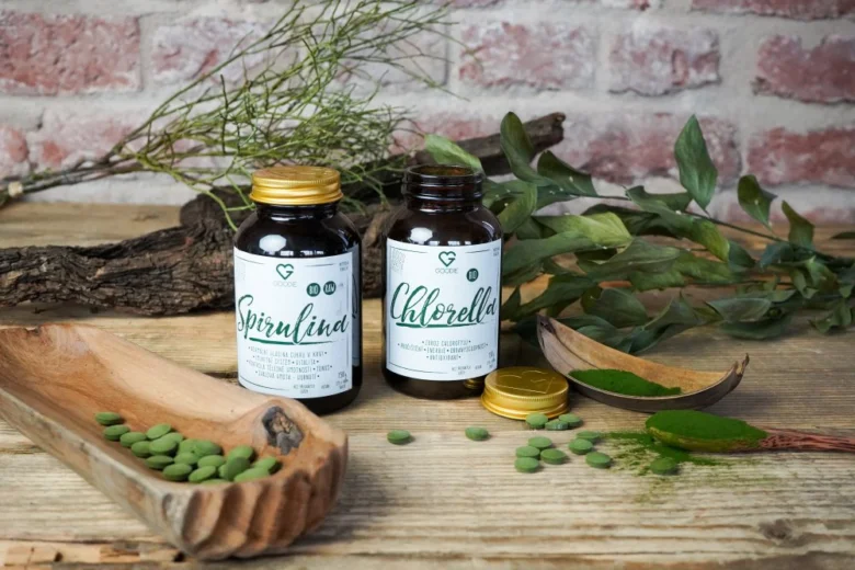 Doplňky stravy s řasami spirulina a chlorella na dřevěném povrchu.