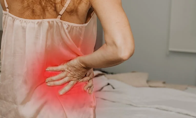 Žena drží dolní část zad kvůli bolesti způsobené skřípnutým nervem.