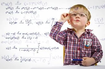 Chlapec s brýlemi u tabule plné matematických rovnic.