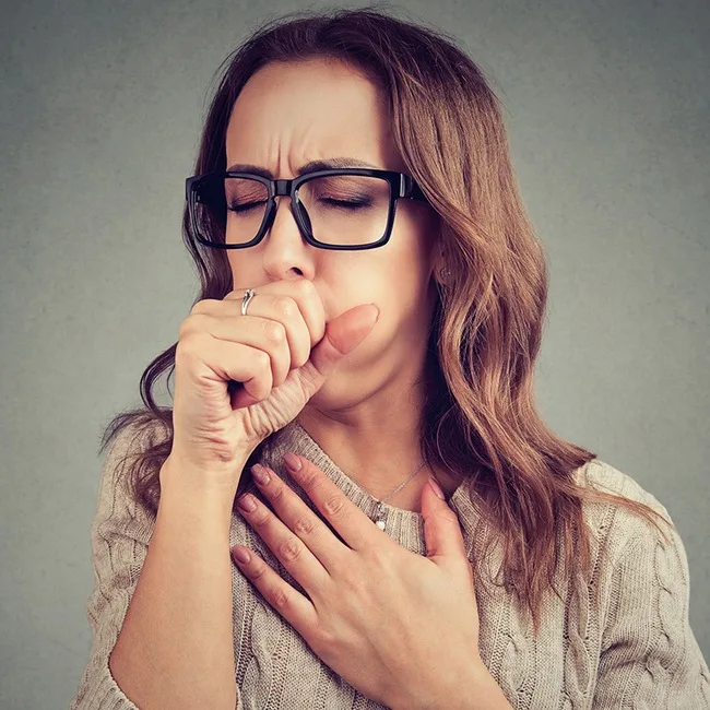 Woman coughing with hand over mouth
